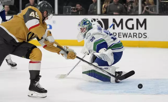 Vegas Golden Knights center Ivan Barbashev (49) scores past Vancouver Canucks goaltender Kevin Lankinen (32) during the second period of an NHL hockey game Saturday, Feb. 22, 2025, in Las Vegas. (AP Photo/John Locher)