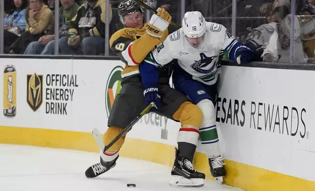 Vegas Golden Knights defenseman Kaedan Korczak (6) checks Vancouver Canucks left wing Drew O'Connor (18) during the third period of an NHL hockey game Saturday, Feb. 22, 2025, in Las Vegas. (AP Photo/John Locher)