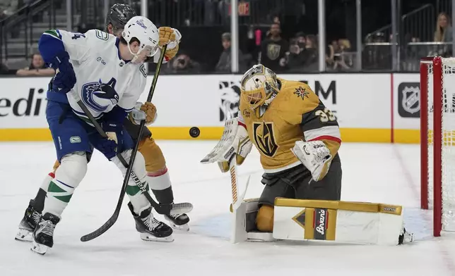 Vegas Golden Knights goaltender Adin Hill (33) blocks a shot beside Vancouver Canucks left wing Jake DeBrusk (74) during the first period of an NHL hockey game Saturday, Feb. 22, 2025, in Las Vegas. (AP Photo/John Locher)
