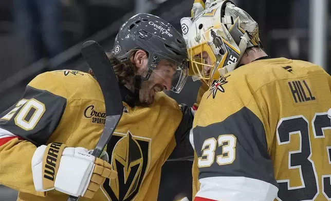 Vegas Golden Knights left wing Brandon Saad (20) and goaltender Adin Hill (33) celebrate after their team defeated the Vancouver Canucks in an NHL hockey game Saturday, Feb. 22, 2025, in Las Vegas. (AP Photo/John Locher)