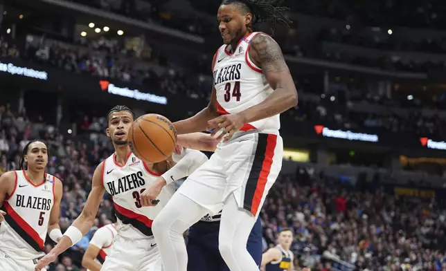 Portland Trail Blazers forward Jabari Walker, front, pulls in a rebound in front of Denver Nuggets center Nikola Jokic in the first half of an NBA basketball game Wednesday, Feb. 12, 2025, in Denver. (AP Photo/David Zalubowski)