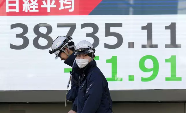 People walk in front of an electronic stock board showing Japan's Nikkei index at a securities firm Monday, Feb. 10, 2025, in Tokyo. (AP Photo/Eugene Hoshiko)
