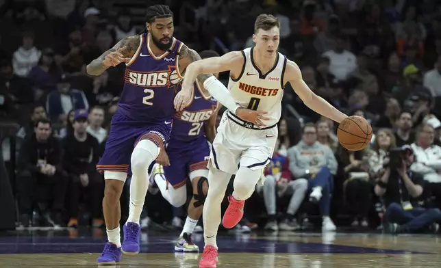 Denver Nuggets guard Christian Braun, right, shields the ball from Phoenix Suns center Nick Richards (2) during the first half of an NBA basketball game, Saturday, Feb. 8, 2025, in Phoenix. (AP Photo/Rick Scuteri)