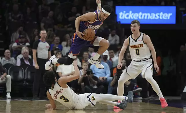 Phoenix Suns guard Devin Booker, top, leaps over Denver Nuggets guard Julian Strawther (3) during the first half of an NBA basketball game, Saturday, Feb. 8, 2025, in Phoenix. (AP Photo/Rick Scuteri)