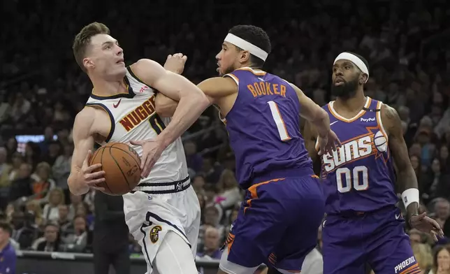 Phoenix Suns guard Devin Booker (1) fouls Denver Nuggets guard Christian Braun, left, during the first half of an NBA basketball game, Saturday, Feb. 8, 2025, in Phoenix. (AP Photo/Rick Scuteri)