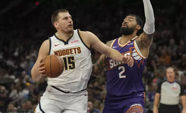 Denver Nuggets center Nikola Jokic (15) drives against Phoenix Suns center Nick Richards (2) during the first half of an NBA basketball game, Saturday, Feb. 8, 2025, in Phoenix. (AP Photo/Rick Scuteri)