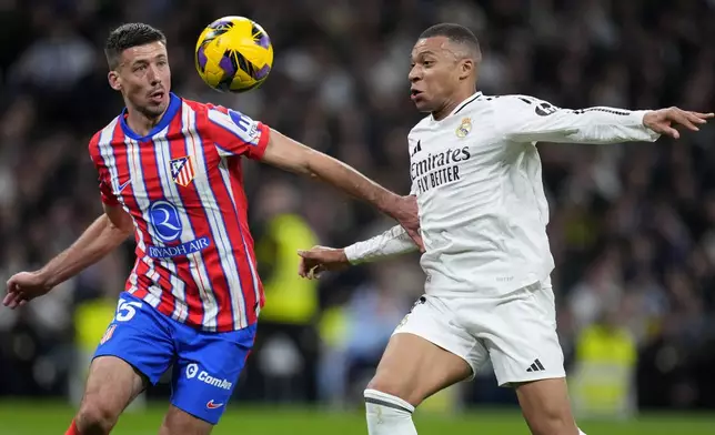 Atletico Madrid's Clement Lenglet vies for the ball with Real Madrid's Kylian Mbappe, right, during a Spanish La Liga soccer match between Real Madrid and Atletico Madrid at the Santiago Bernabeu stadium in Madrid, Saturday, Feb. 8, 2025. (AP Photo/Manu Fernandez)
