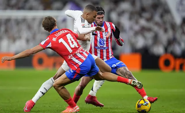 Real Madrid's Kylian Mbappe vies for the ball with Atletico Madrid's Marcos Llorenteleft, and Rodrigo De Paul, right, during a Spanish La Liga soccer match between Real Madrid and Atletico Madrid at the Santiago Bernabeu stadium in Madrid, Saturday, Feb. 8, 2025. (AP Photo/Manu Fernandez)