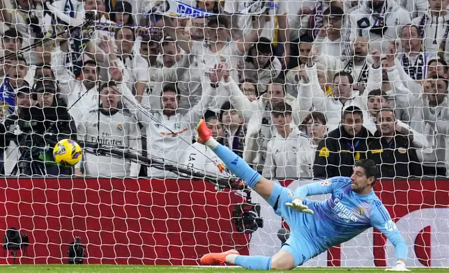 Real Madrid's goalkeeper Thibaut Courtois fails to stop a penalty shot by Atletico Madrid's Julian Alvarez during a Spanish La Liga soccer match between Real Madrid and Atletico Madrid at the Santiago Bernabeu stadium in Madrid, Saturday, Feb. 8, 2025. (AP Photo/Manu Fernandez)