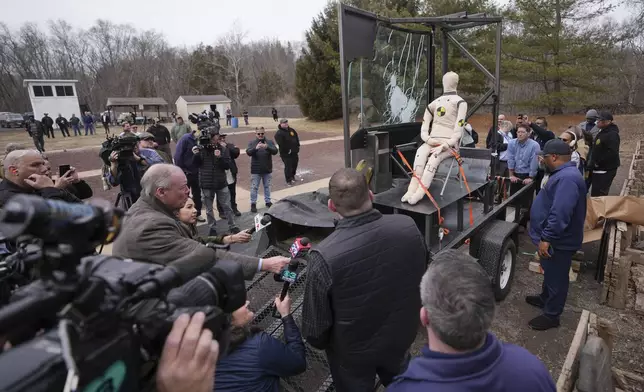 People inspect bullet-resistant enclosures to be installed on buses, after it was fired pond during a demonstration at a range in Bedminster, Pa., Tuesday, Feb. 25, 2025. (AP Photo/Matt Rourke)