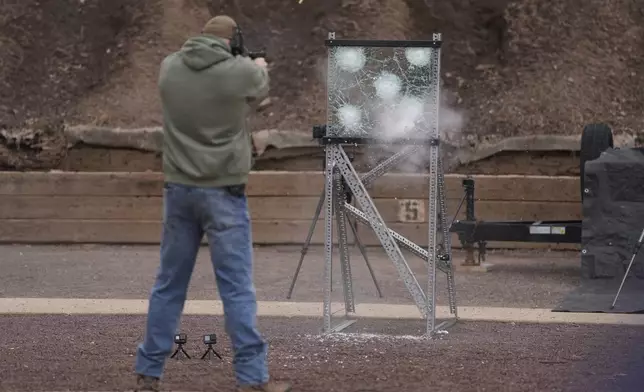 An officer fires a weapon at a sample of the material used in bullet-resistant enclosures to be installed on buses, at a range in Bedminster, Pa., Tuesday, Feb. 25, 2025. (AP Photo/Matt Rourke)