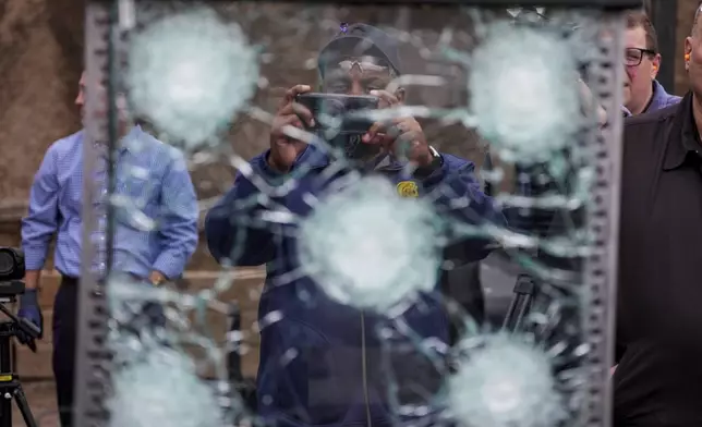 Tyson Brown, president of Transportation Workers Union Local 208, photographs a sample of the material used in bullet-resistant enclosures to be installed on buses, that was fired upon at a range in Bedminster, Pa., Tuesday, Feb. 25, 2025. (AP Photo/Matt Rourke)