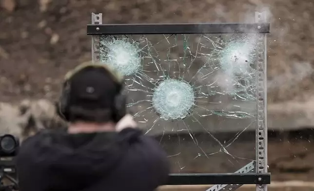 An officer fires a weapon at a sample of the material used in bullet-resistant enclosures to be installed on buses, at a range in Bedminster, Pa., Tuesday, Feb. 25, 2025. (AP Photo/Matt Rourke)