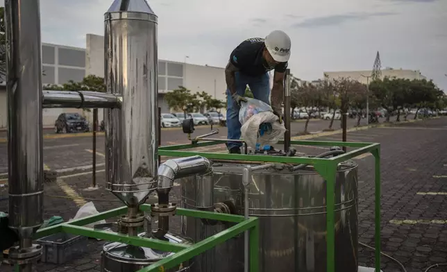 Jesus Cuevas, a Petgas technician, throws plastic into Petgaserita, a non-catalytic pyrolysis machine, to convert it into fuel, in Boca del Rio, Veracruz, Mexico, Jan. 4, 2025. (AP Photo/Felix Marquez)
