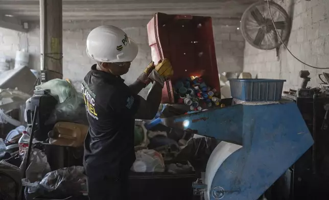 Jesus Cuevas, a Petgas technician, puts plastic caps into a shredding machine inside a recycling center in Boca del Rio, Veracruz, Mexico, Jan. 4, 2025. (AP Photo/Felix Marquez)
