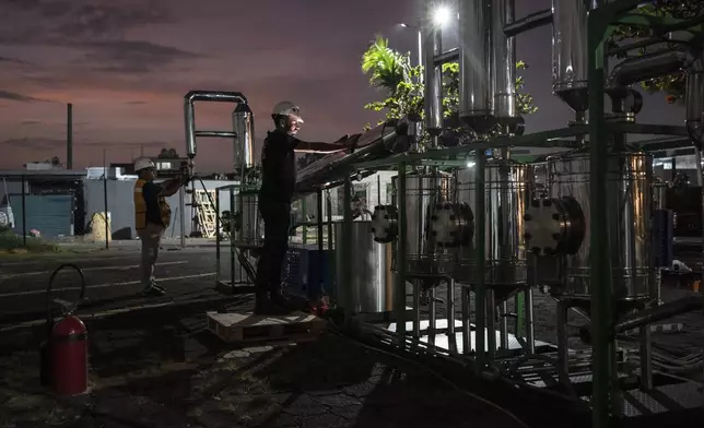 Edgar Pedroza and Carlos Parraguirre Diaz maintain and clean Petgaserita, a non-catalytic pyrolysis machine that converts plastic into fuel, after a demonstration operation in Boca del Rio, Veracruz, Mexico, Jan. 4, 2025. (AP Photo/Felix Marquez)