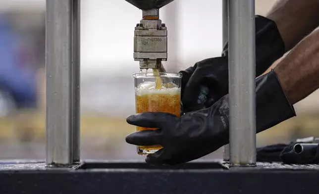 Carlos Parraguirre Diaz, head of technical operations at Petgas, obtains fuel during a demonstration operation of Petgaserita, a non-catalytic pyrolysis machine that converts plastic into fuel, n Boca del Rio, Veracruz, Mexico, Jan. 4, 2025. (AP Photo/Felix Marquez)