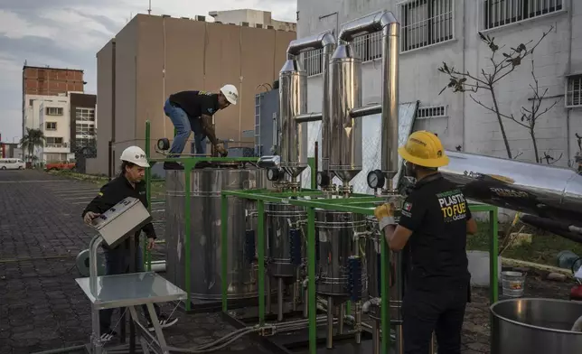 Jesus Cuevas, center, Daniel Rodriguez, left, and Carlos Parraguirre Diaz, right, run a demonstration operation of Petgaserita, a non-catalytic pyrolysis machine that converts plastic into fuel, in Boca del Rio, Veracruz, Mexico, Jan. 4, 2025. (AP Photo/Felix Marquez)