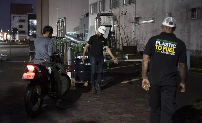 Carlos Parraguirre Diaz and Jesús Cuevas pump Petgas gasoline, made from plastic, to a motorcyclist in Boca del Rio, Veracruz, Mexico, Jan. 4, 2025. (AP Photo/Felix Marquez)