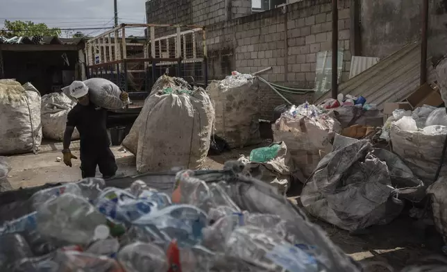 Jesus Cuevas, a Petgas technician, carries a bag filled with shredded plastic, at a recycling center in Boca del Rio, Veracruz, Mexico, Jan. 4, 2025. (AP Photo/Felix Marquez)
