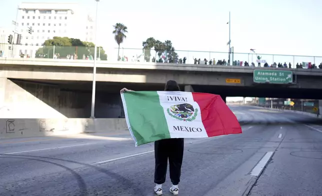 CORRECTS NAME OF THE FREEWAY - A demonstrator holds a Mexican flag while standing on the 101 freeway during a protest calling for immigration reform Sunday, Feb. 2, 2025, in Los Angeles. (AP Photo/Eric Thayer)