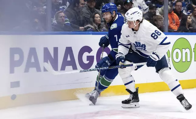 Vancouver Canucks' Carson Soucy (7) and Toronto Maple Leafs' William Nylander (88) vie for the puck during the second period of an NHL hockey game in Vancouver, on Saturday, Feb. 8, 2025. (Ethan Cairns/The Canadian Press via AP)