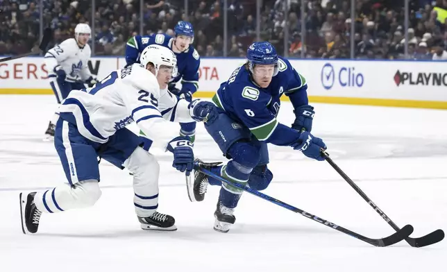 Toronto Maple Leafs' Pontus Holmberg (29) and Vancouver Canucks' Brock Boeser (6) vie for the puck during the first period of an NHL hockey game in Vancouver, British Columbia, Saturday, Feb. 8, 2025. (Ethan Cairns/The Canadian Press via AP)