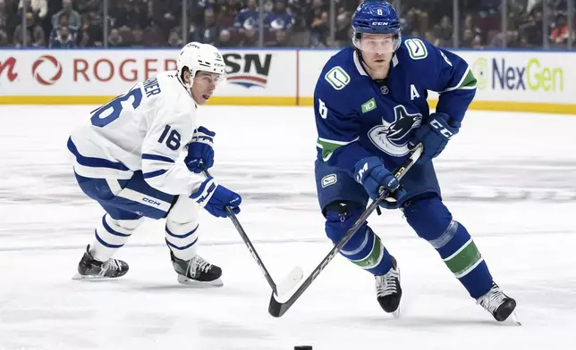 Vancouver Canucks' Brock Boeser (6) skates with the puck as Toronto Maple Leafs' Mitch Marner (16) defends during the first period of an NHL hockey game in Vancouver, British Columbia, Saturday, Feb. 8, 2025. (Ethan Cairns/The Canadian Press via AP)
