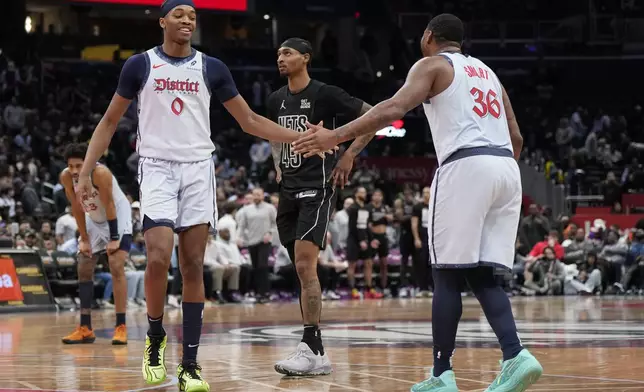 Washington Wizards guards Bilal Coulibaly (0) and Marcus Smart (36) high-five as Brooklyn Nets guard Keon Johnson looks on during the second half of an NBA basketball game, Monday, Feb. 24, 2025, in Washington. (AP Photo/Jess Rapfogel)