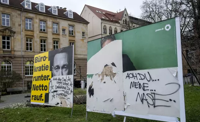 Defaces election posters of Green Party top candidate and federal minister for economy Robert Habeck, right, and FDP top candidate and former finance minister Christian Lindner, are seen is a street, in Magdeburg, Germany, Friday, Feb. 7, 2025. (AP Photo/Ebrahim Noroozi)