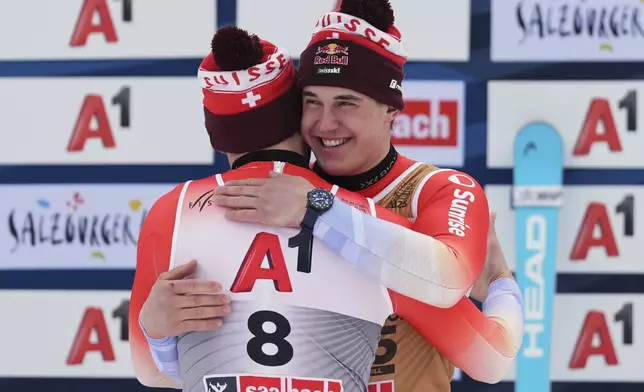 Switzerland's Alexis Monney, back to camera, bronze medalist in a men's downhill race, hugs gold medalist Switzerland's Franjo von Allmen, at the Alpine Ski World Championships, in Saalbach-Hinterglemm, Austria, Sunday, Feb. 9, 2025. (AP Photo/Giovanni Auletta)