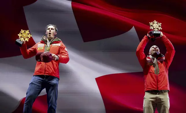 Switzerland's Franjo von Allmen, left, shows his gold medal for a men's downhill race, next to bronze medalist Switzerland's Alexis Monney, at the Alpine Ski World Championships, in Saalbach-Hinterglemm, Austria, Sunday, Feb. 9, 2025. (Jean-Christophe Bott/Keystone via AP)