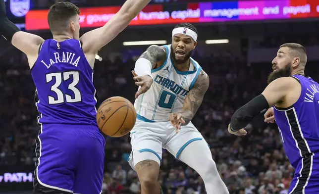Charlotte Hornets forward Miles Bridges (0) passes the ball past Sacramento Kings forward Jake LaRavia (33) and Jonas Valanciunas, right, during the first half of an NBA basketball game in Sacramento, Calif., Monday, Feb. 24, 2025. (AP Photo/Randall Benton)