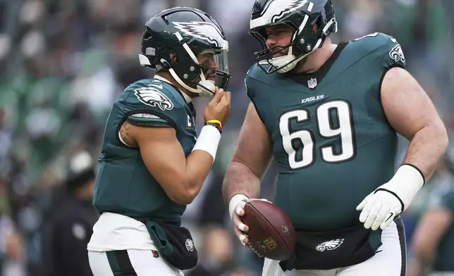 Philadelphia Eagles quarterback Jalen Hurts, left, talks to Landon Dickerson (69) during warm ups before the NFC Championship NFL football game against the Washington Commanders, Sunday, Jan. 26, 2025, in Philadelphia. (AP Photo/Matt Slocum)