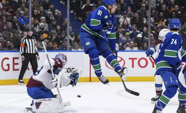 Vancouver Canucks' Dakota Joshua (81) jumps to avoid the puck as it goes wide of the net behind Colorado Avalanche goalie MacKenzie Blackwood (39) during the third period of an NHL hockey game in Vancouver, British Columbia, Tuesday, Feb. 4, 2025. (Darryl Dyck/The Canadian Press via AP)