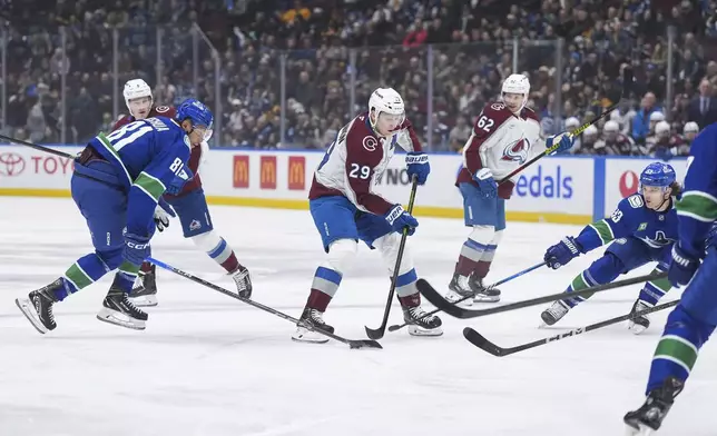 Colorado Avalanche's Nathan MacKinnon (29) loses the puck to Vancouver Canucks' Dakota Joshua (81) as Teddy Blueger (53) defends during the first period of an NHL hockey game in Vancouver, British Columbia, Tuesday, Feb. 4, 2025. (Darryl Dyck/The Canadian Press via AP)