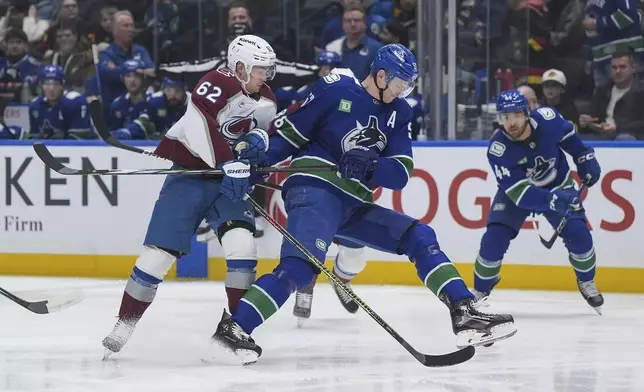 Colorado Avalanche's Artturi Lehkonen (62) checks Vancouver Canucks' Tyler Myers (57) during the first period of an NHL hockey game in Vancouver, British Columbia, Tuesday, Feb. 4, 2025. (Darryl Dyck/The Canadian Press via AP)