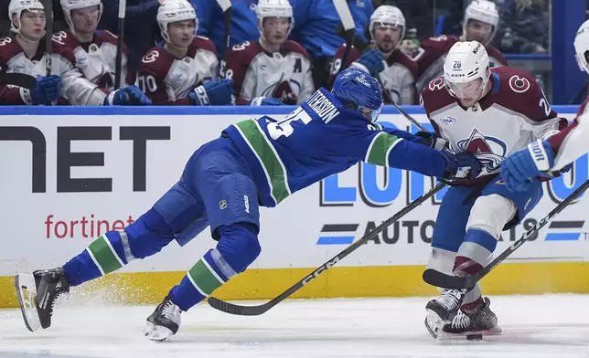Vancouver Canucks defenseman Elias Pettersson (25) checks Colorado Avalanche's Ross Colton (20) during the second period of an NHL hockey game in Vancouver, on Tuesday, Feb. 4, 2025. (Darryl Dyck/The Canadian Press via AP)