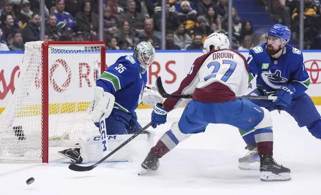 Colorado Avalanche's Jonathan Drouin (27) fails to get his stick on the puck in front of Vancouver Canucks goalie Thatcher Demko (35) while being checked by Filip Hronek (17) during the second period of an NHL hockey game in Vancouver, on Tuesday, Feb. 4, 2025. (Darryl Dyck/The Canadian Press via AP)
