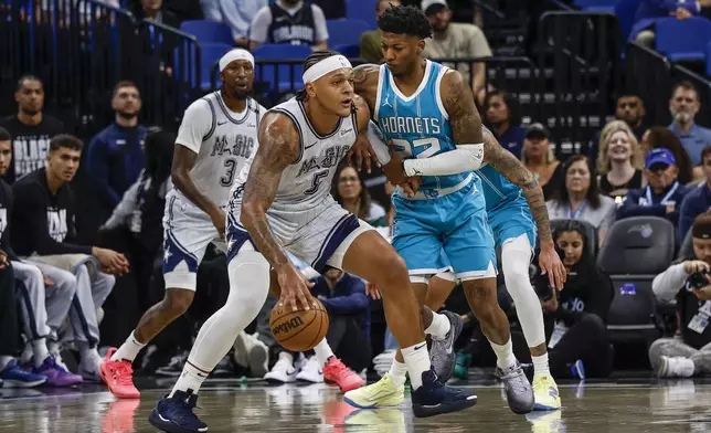 Orlando Magic forward Paolo Banchero (5) is defended by Charlotte Hornets guard Elfrid Payton during the first half of an NBA basketball game, Wednesday, Feb. 12, 2025, in Orlando, Fla. (AP Photo/Kevin Kolczynski)