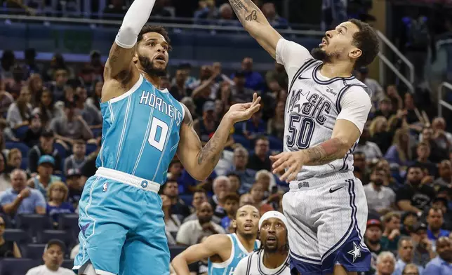 Charlotte Hornets forward Miles Bridges (0) shoots the ball over Orlando Magic guard Cole Anthony (50) during the first half of an NBA basketball game, Wednesday, Feb. 12, 2025, in Orlando, Fla. (AP Photo/Kevin Kolczynski)