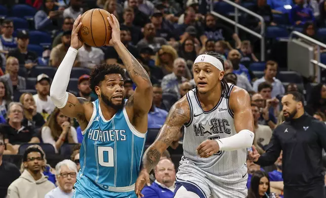 Charlotte Hornets forward Miles Bridges (0) steps past Orlando Magic forward Paolo Banchero towards the basket during the first half of an NBA basketball game, Wednesday, Feb. 12, 2025, in Orlando, Fla. (AP Photo/Kevin Kolczynski)