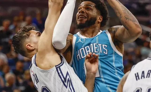 Charlotte Hornets forward Miles Bridges, right, goes up to shoot as he is defended by Orlando Magic forward Tristan da Silva, left, during the first half of an NBA basketball game, Wednesday, Feb. 12, 2025, in Orlando, Fla. (AP Photo/Kevin Kolczynski)