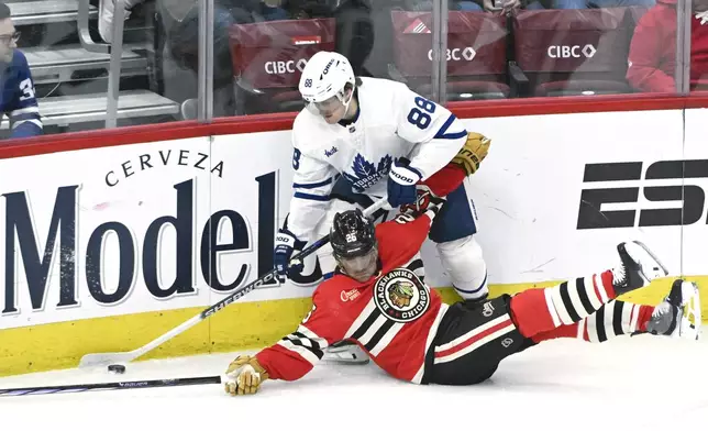 Toronto Maple Leafs right wing William Nylander (88) and Chicago Blackhawks defenseman Alec Martinez (25) chase the puck during the second period of an NHL hockey game, Sunday, Feb. 23, 2025, in Chicago. (AP Photo/Matt Marton)