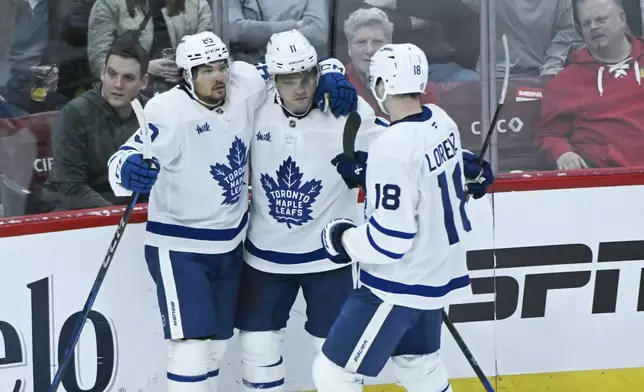 Toronto Maple Leafs left wing Nicholas Robertson celebrates with center Max Domi (11) and center Steven Lorentz (18) after he scores a goal against the Chicago Blackhawks during the second period of an NHL hockey game, Sunday, Feb. 23, 2025, in Chicago. (AP Photo/Matt Marton)