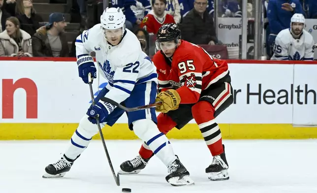 Toronto Maple Leafs defenseman Jake McCabe (22) and Chicago Blackhawks right wing Ilya Mikheyev (95) fight for the puck during the first period of an NHL hockey game, Sunday, Feb. 23, 2025, in Chicago. (AP Photo/Matt Marton)