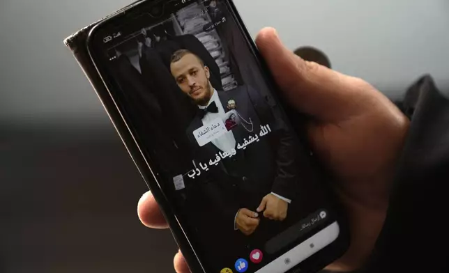 Mohammed Shula displays an undated picture of his son Yazan, while inside a relative's house where he and his wife have taken refuge at the West Bank village of Kafr al-Labad, Monday, Feb. 10, 2025. (AP Photo/Nasser Nasser)
