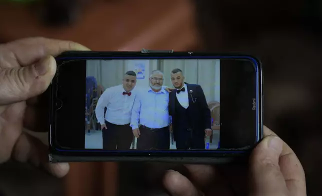 Mohammed Shula displays a picture on his cellphone of him, center and his sons Bilal and Yazan, inside a relative's house where he and his wife have taken refuge in the West Bank village of Kafr al-Labad, Monday, Feb. 10, 2025. (AP Photo/Nasser Nasser)