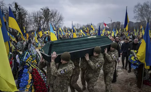 FILE - Ukrainian servicemen carry the coffin of their comrade Andrii Neshodovskiy during the funeral ceremony at the cemetery in Kyiv, Ukraine, Saturday, March 25, 2023. (AP Photo/Evgeniy Maloletka, File)