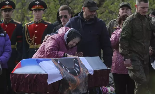 FILE - A relative of Shashkov Savely, a volunteer of detachment "Immortal Stalingrad" in the Russian Army, who was killed during a Russian special military operation in Ukraine, pays her last respect during his farewell ceremony at a cemetery in Krasnoslobodsk, Volgograd region, Russia, Saturday, April 15, 2023. (AP Photo, File)